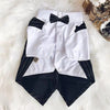 A white shirt with black accents and a black bow tie laid on a white fluffy surface.