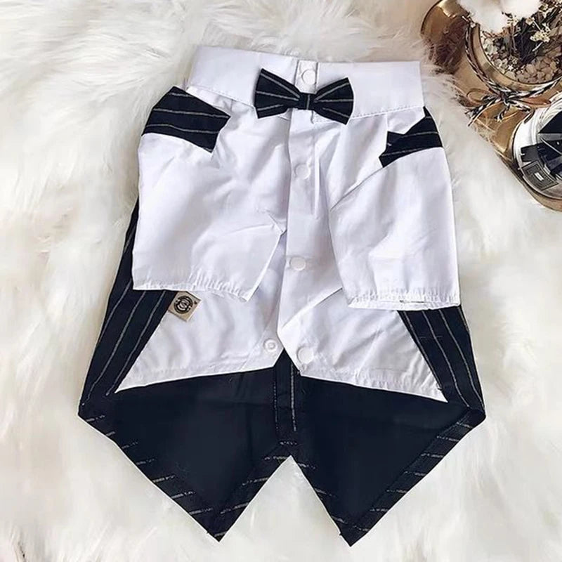 A white shirt with black accents and a black bow tie laid on a white fluffy surface.