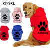 A golden retriever wearing a red hoodie with a paw print design, alongside various colored Adidog dog hoodies.