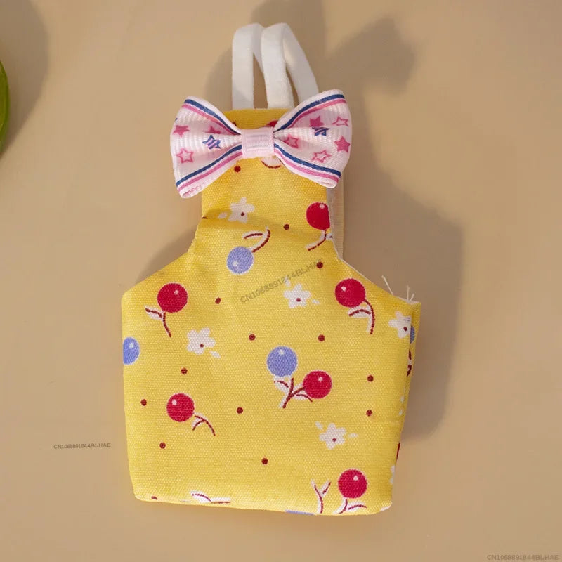 Yellow fabric parrot flight suit with a pink bow tie and scattered red and blue floral designs.