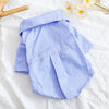 A light blue and white striped bowknot shirt for a small dog lying on a white surface.