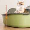 A fluffy orange tabby cat is sitting inside a light green semi-enclosed splashproof litter box with a scoop.