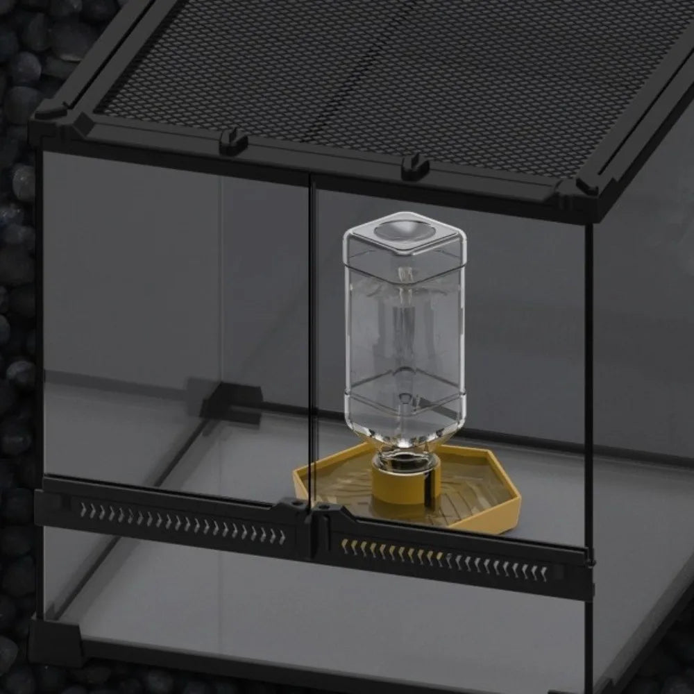 Ein durchsichtiger Glasbehälter für Wasser wird in eine schwarze Acrylbox für ein automatisiertes Reptilien-Wassersystem gele