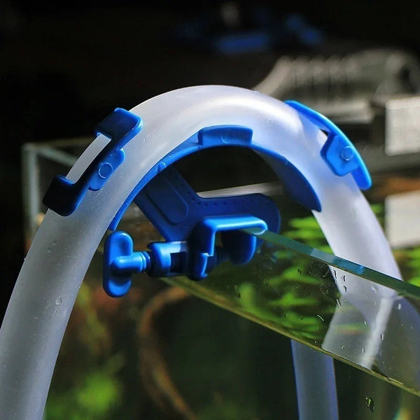 A close-up of a blue plastic aquarium hose holder clip used to secure filtration tubes.