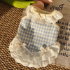 A white and blue gingham pet dress for a small dog with lace trim and bow details.