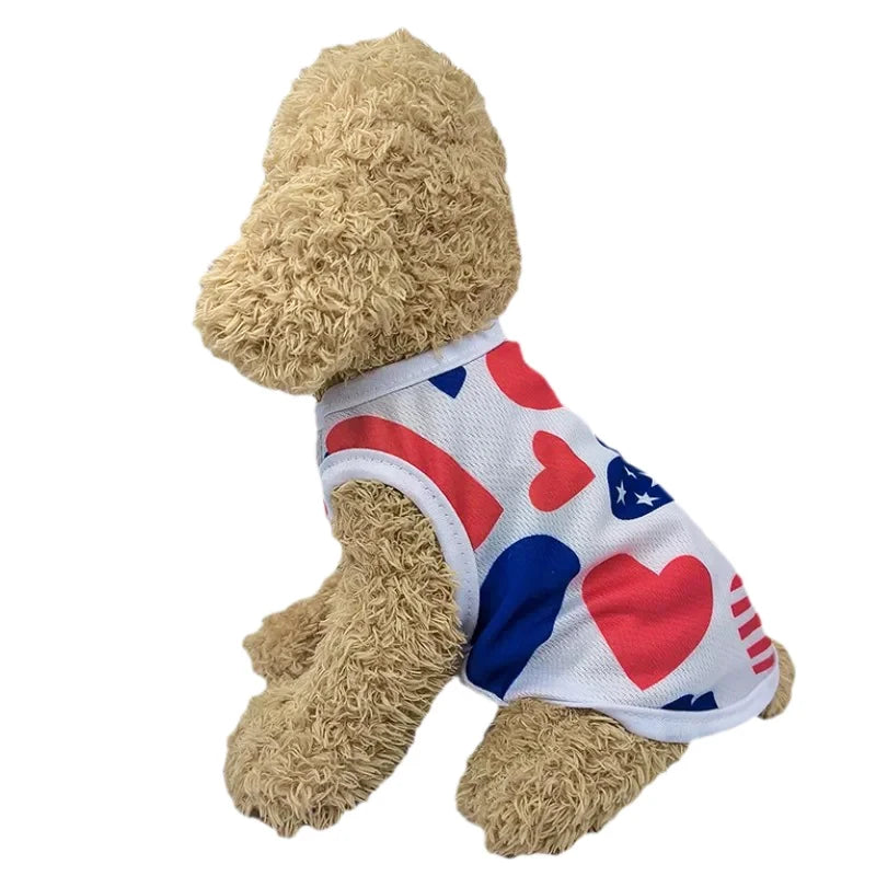 A light brown dog wearing a patriotic Independence Day vest featuring red, white, and blue patterns.