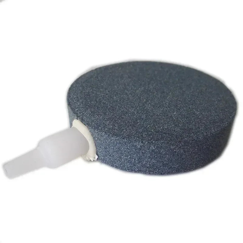 A round, dark gray air stone disc with a white connector for aquarium aeration.