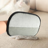 A pair of pet hair removal grooming gloves with a gray and white textured pad resting on a beige surface.