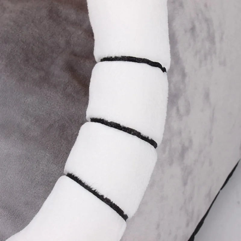A close-up of a white, cylindrical pet cave bed with black trim, resting on a gray fabric.