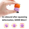 A hand is squeezing two soft plush balls, one orange and one purple, demonstrating a rebound effect.