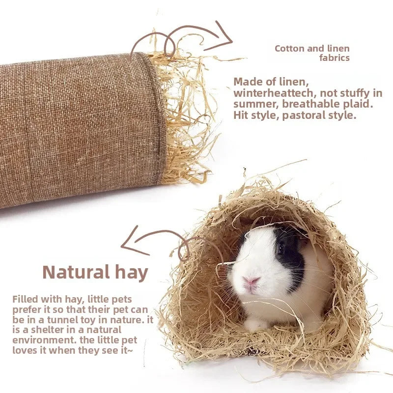 A small white and black pet is nestled inside a natural hay tunnel hideout made of straw and linen fabrics.