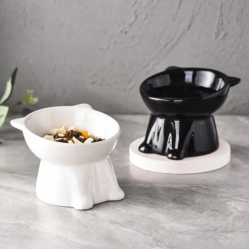 A black elevated slanted cat bowl with an anti-tip base sitting on a light gray surface.
