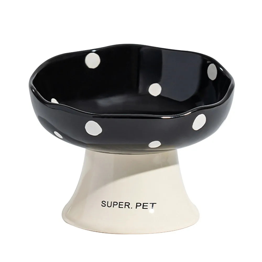 Black ceramic pet bowl with white polka dots resting on a light-colored pedestal.