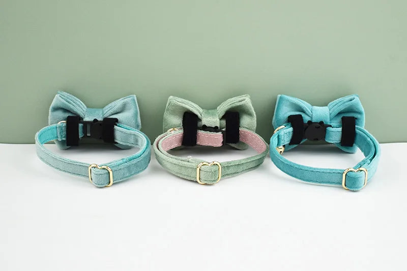 Three velvet cat collars in mint green, teal, and light blue with black safety buckles and bow knots.