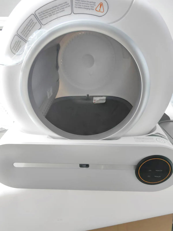 A white cat litter box accessory bin with a circular opening and a control panel below.