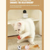 Eine weiße Katze interagiert mit einem roten elastischen Ballspielzeug auf einem Teppich.