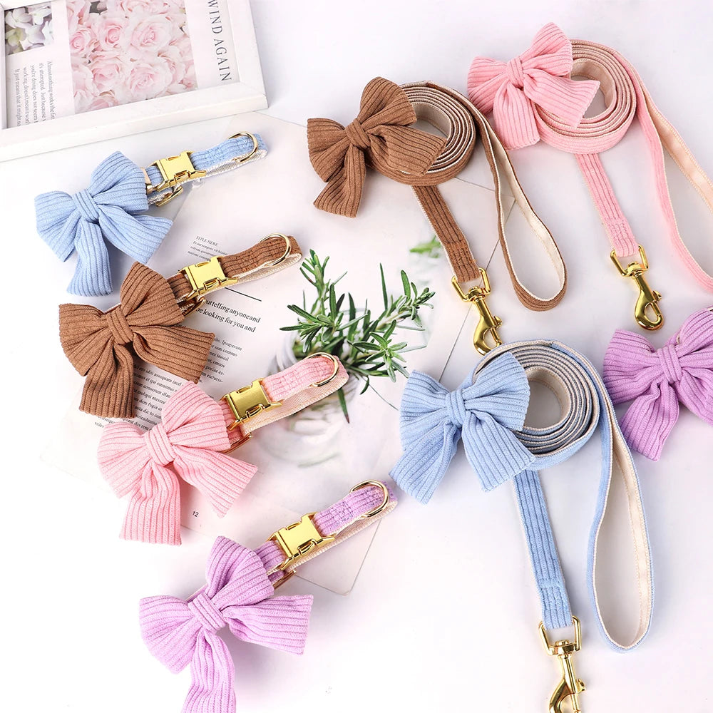 A collection of pink, blue, and beige velvet dog collars and leashes featuring bowknot designs.
