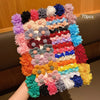 A large assortment of 70 fabric hair clips in various colors and floral patterns displayed on a wooden surface.