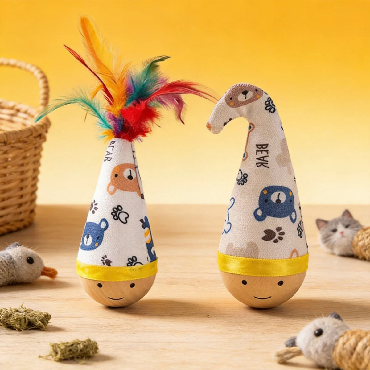 A knitted cat wobble toy with colorful feathers is shown on a wooden surface.
