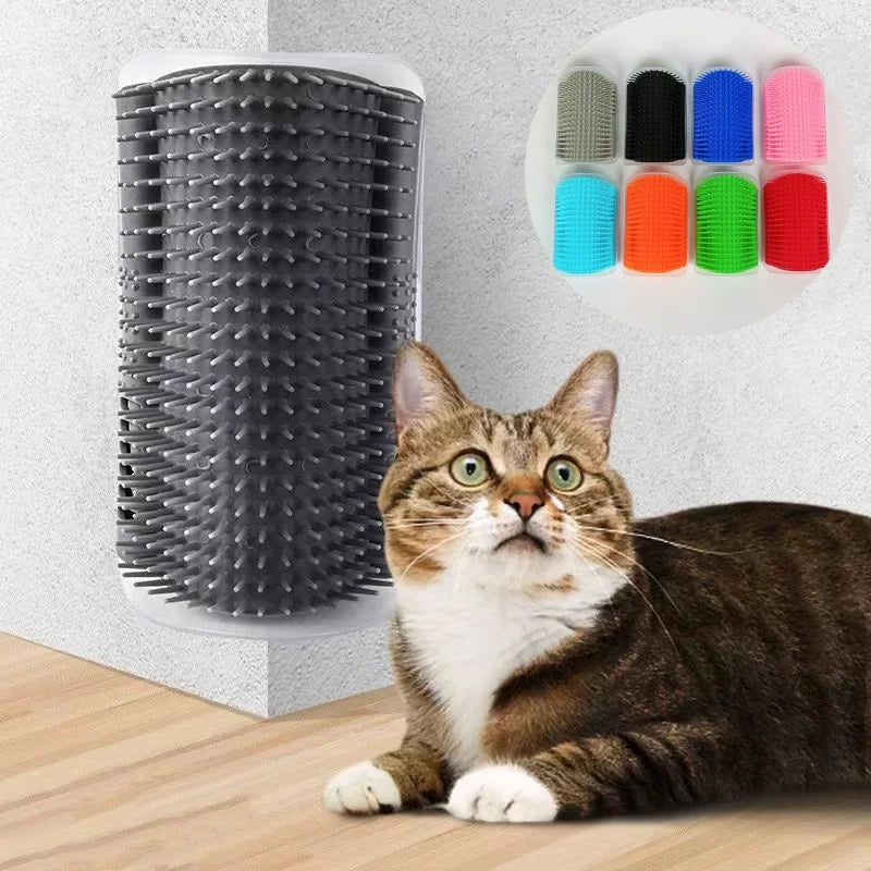 A tabby cat looks up at a white plastic hair removal brush with multiple colored bristles mounted on a wall.