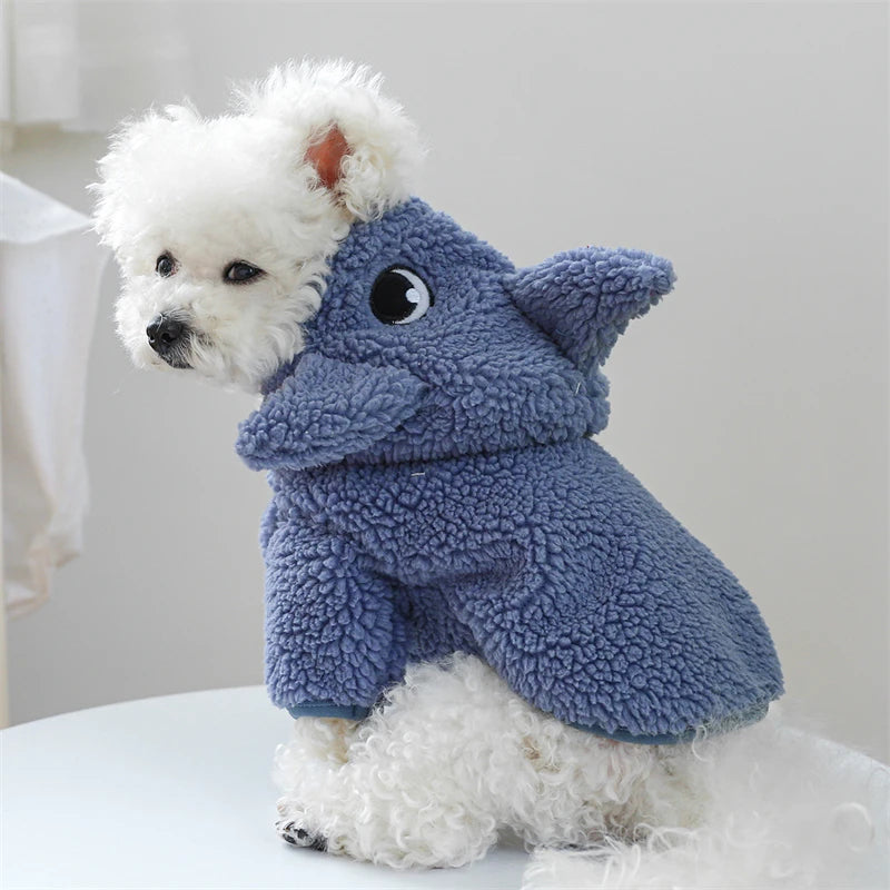 A fluffy white dog wearing a blue fleece pet overalls.