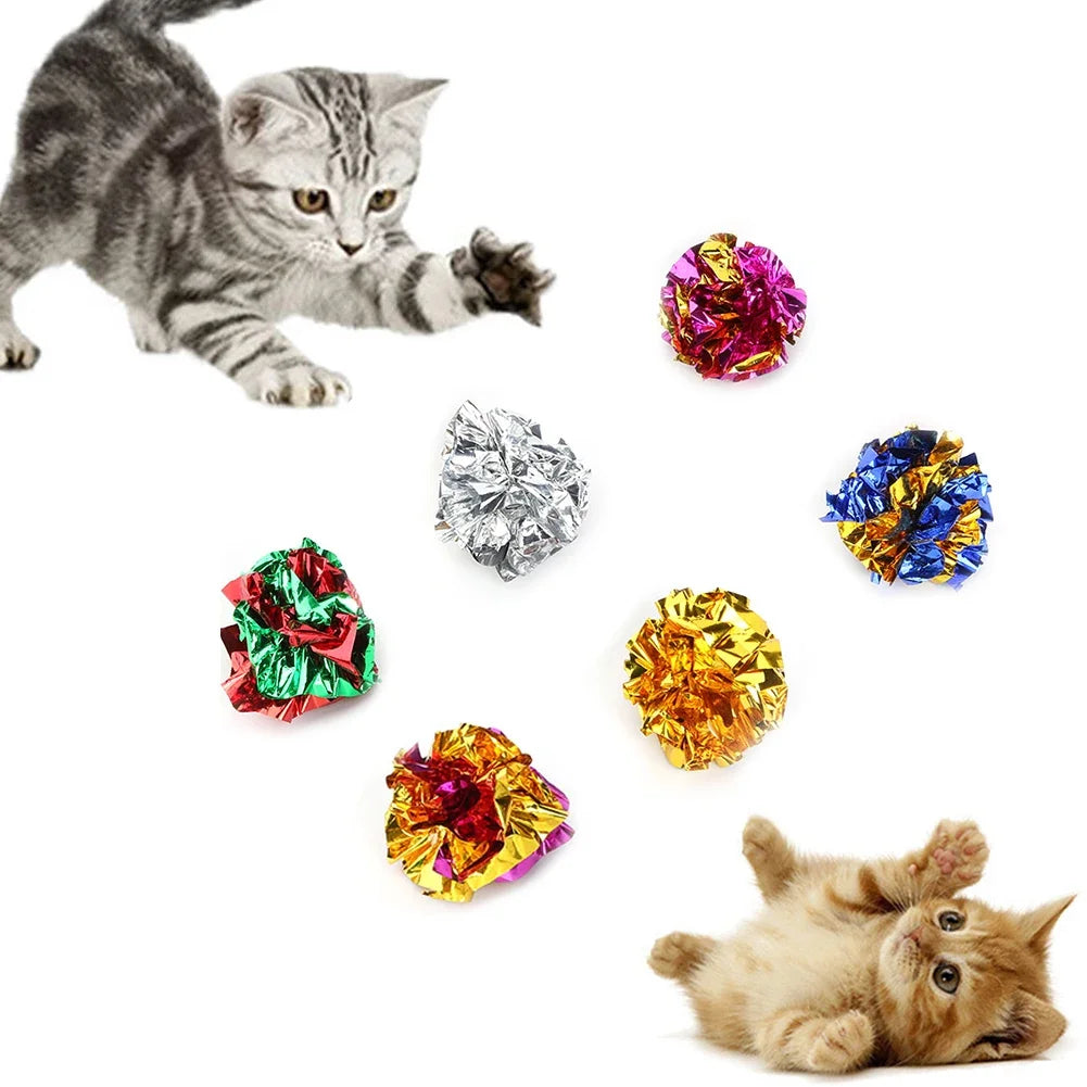 A tabby cat is playing with various colorful crinkle balls and a small kitten.