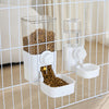 A white automatic pet feeder containing dry food and a separate waterer bowl, viewed through a wire mesh cage.