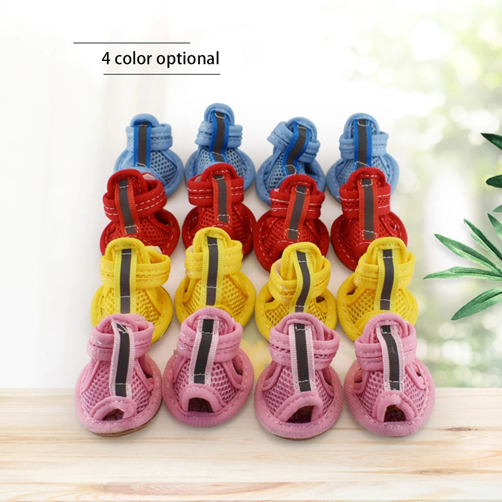A set of four colorful breathable summer dog shoes in blue, red, yellow, and pink are displayed on a wooden surface.