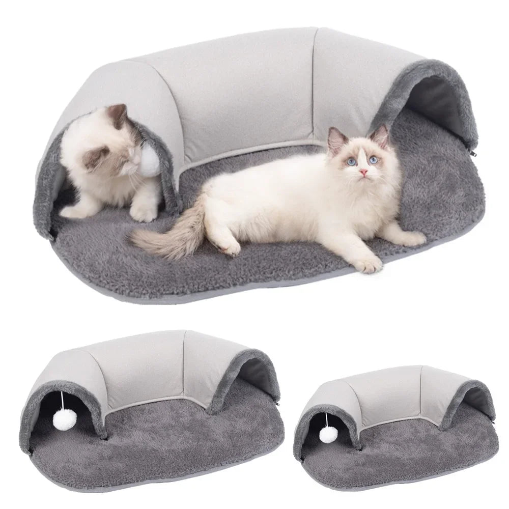 A gray oval cat tunnel and cozy bed nest with a white cat resting inside.