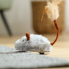 A small, fluffy gray mouse cat toy with an orange tail is resting on a gray fabric surface.