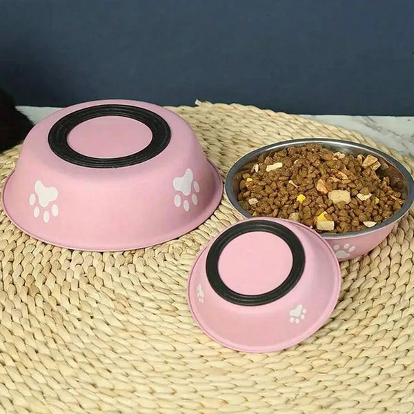 Pink stainless steel pet bowl with a non-slip silicone base resting on a woven mat.