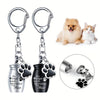 Stainless steel memorial pet ashes keychain with paw print charms attached to a silver and black container.