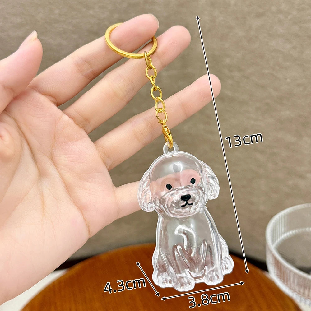 A clear glass puppy charm keychain is held in a hand, showing its size and detail.