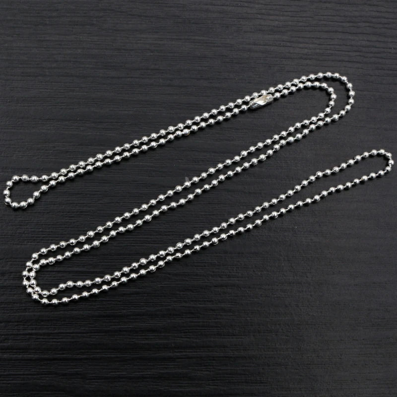 A set of gold and silver plated ball necklaces laid diagonally on a dark surface.