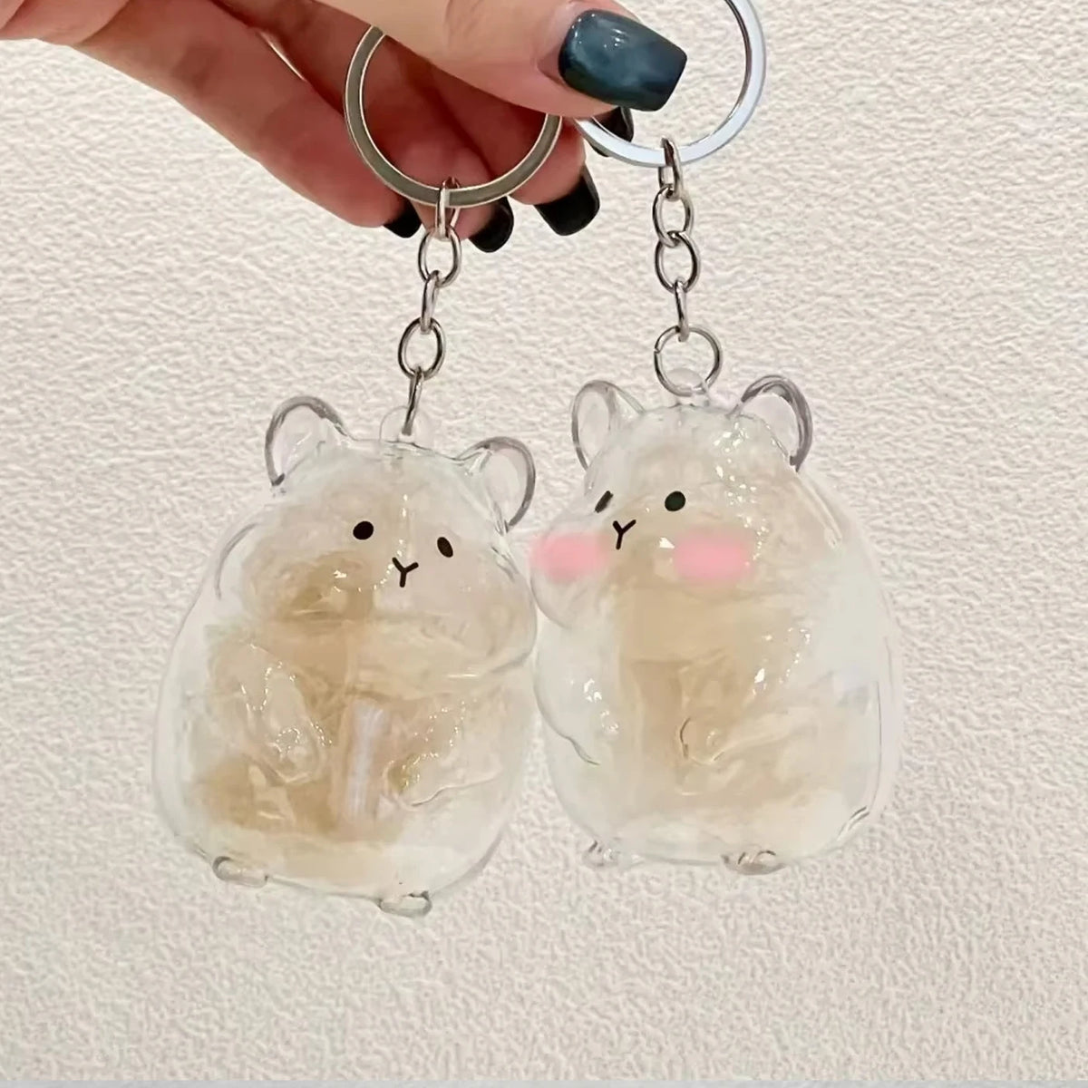 Clear glass hamster figurine keychain with pink accents hanging from silver hoop earrings