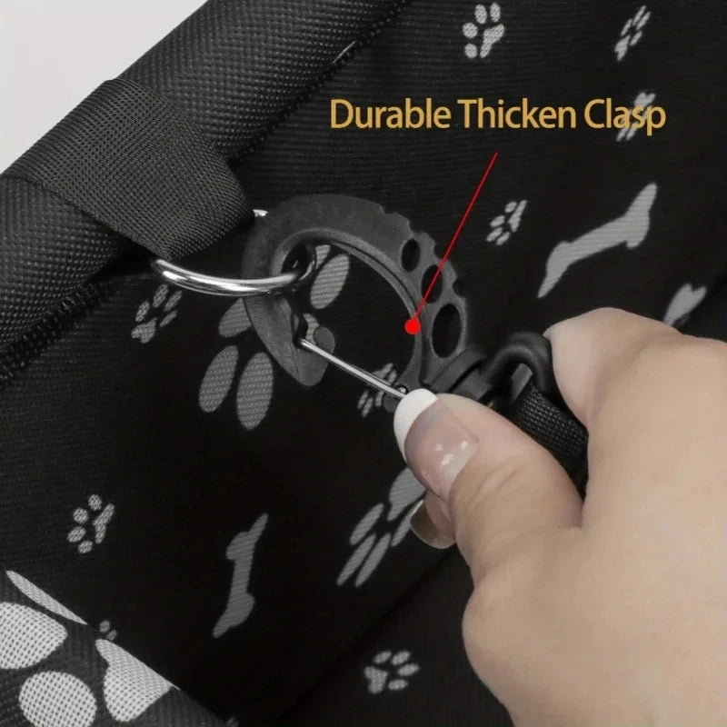 A hand is shown engaging a durable thick clasp on a black pet travel booster seat with a safety belt for dogs and cats.