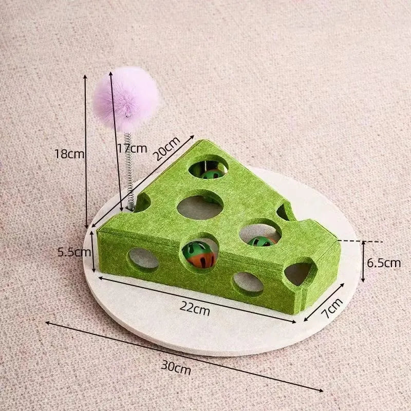 A green felt puzzle maze shaped like a cat with holes, next to a pink pom-pom and a ruler.