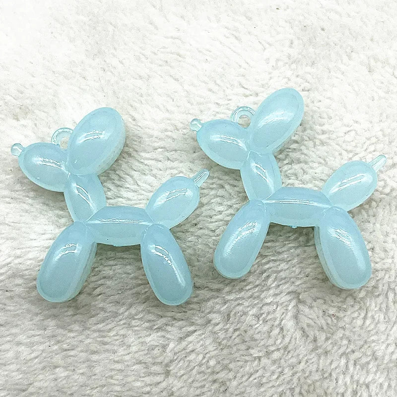 Two light blue acrylic balloon dog charm pendants displayed on a white, fuzzy surface.