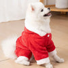 A white dog wearing a red fuzzy jumpsuit costume.