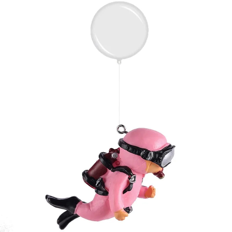 A pink resin mini diver aquarium ornament with black gear is suspended beneath a white balloon.