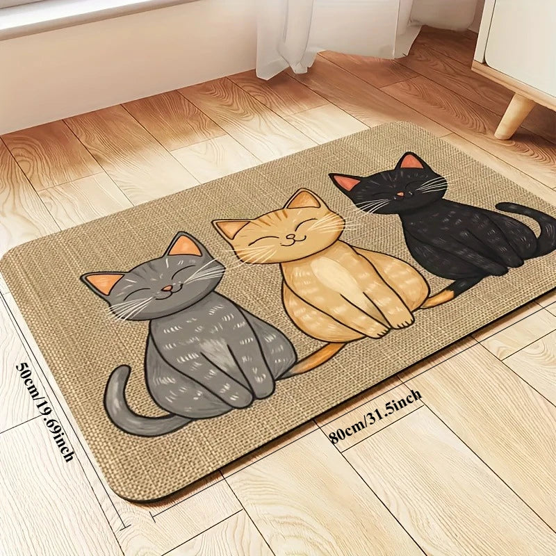 A rectangular beige pet feeding mat featuring a watercolor illustration of three cats in shades of gray, orange, and black.