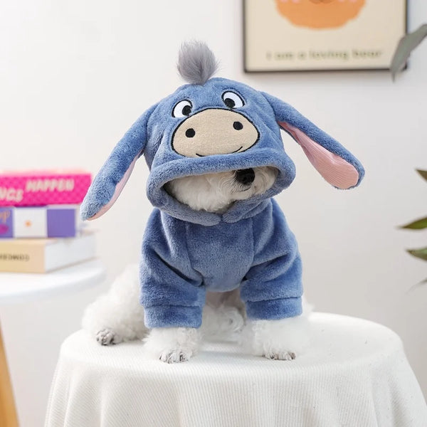 Flauschiger blauer Flanell-Hoodie Hund in hellblauer Strickkleidung sitzt auf weißem Tisch.