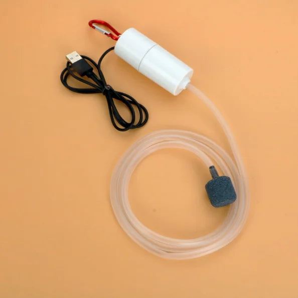 A white portable USB aquarium oxygen pump with a clear tubing and a small black adapter is shown on a beige background.