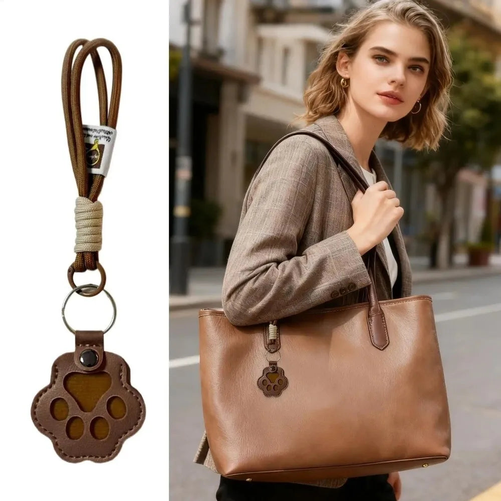 A woman holds a brown leather handbag and a pet hair keychain with a cat paw charm.