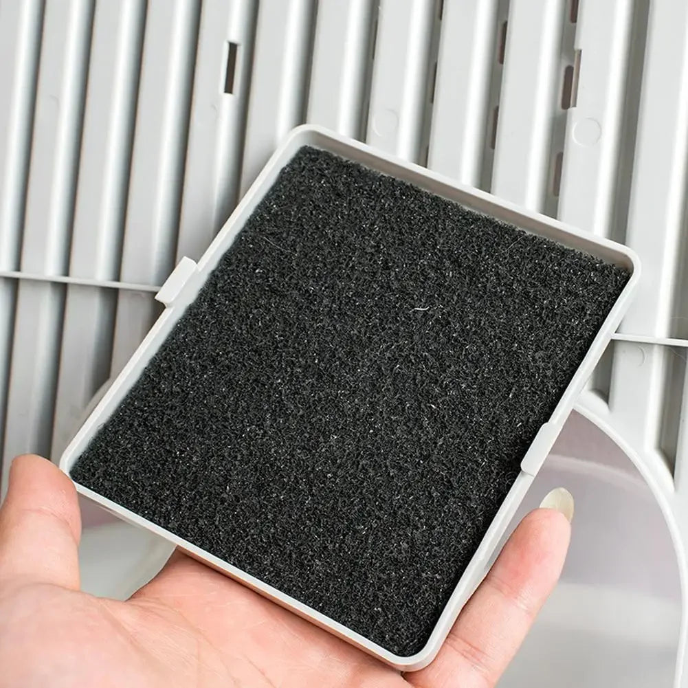 A hand holds a rectangular black filter pad for an activated carbon litter box filter system.