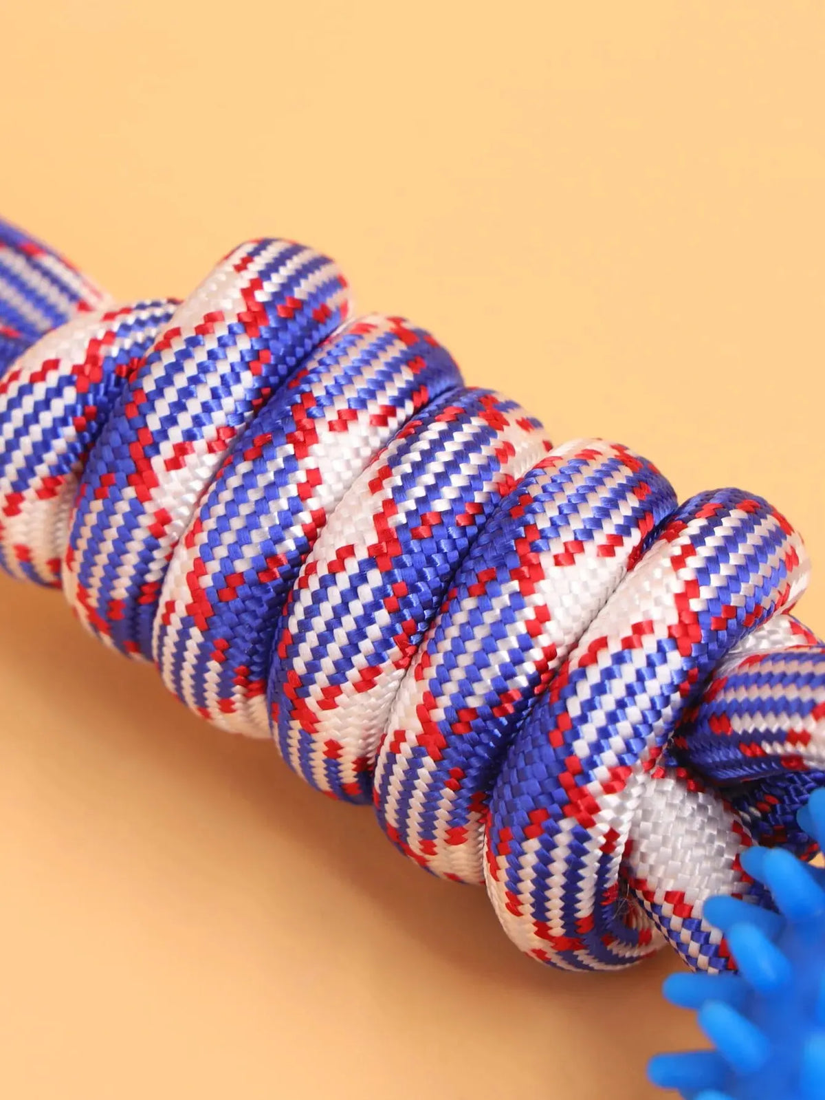 A close-up of a blue and white rope chew ring for dogs coiled on a light background.
