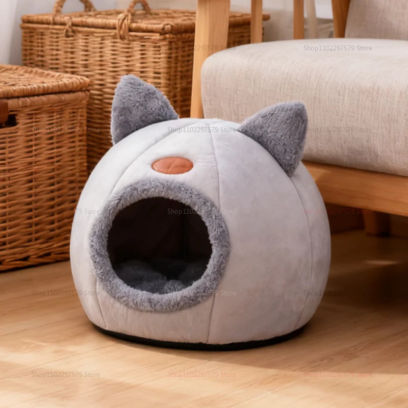 Un nid pour chat moelleux gris rond avec de grandes oreilles et un nez orange sur un plancher en bois.