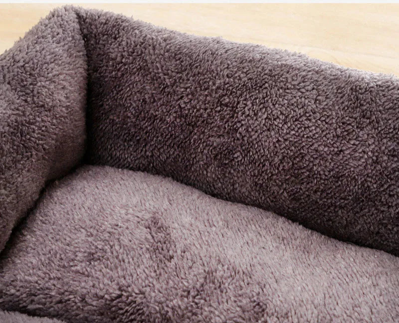 A close-up view of a dark gray, plush dog bed with a soft, textured cover.