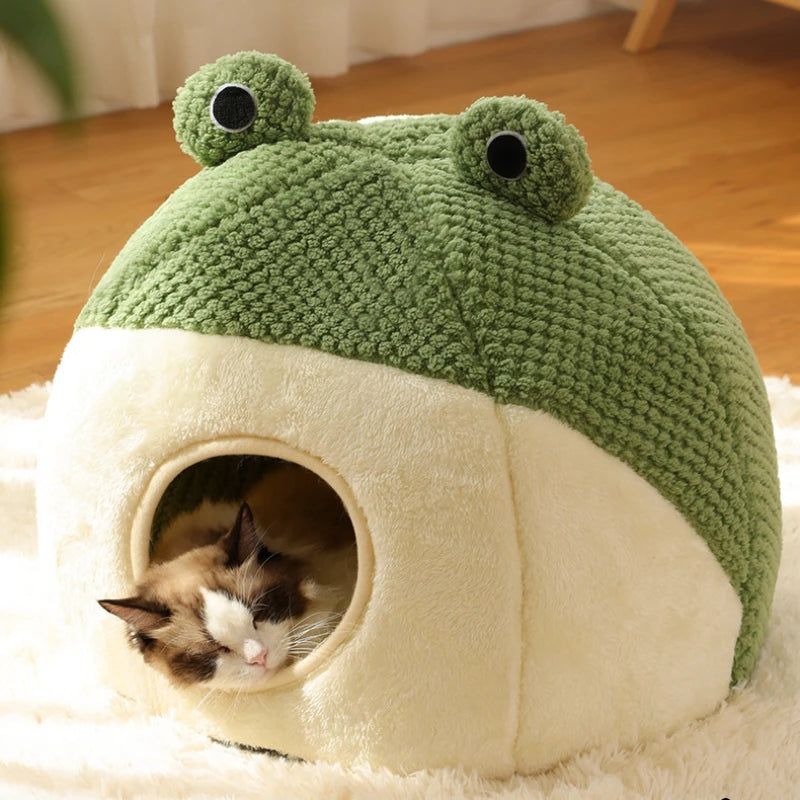 Nido de peluche verde con base blanca, conteniendo un pequeño gatito atigrado.
