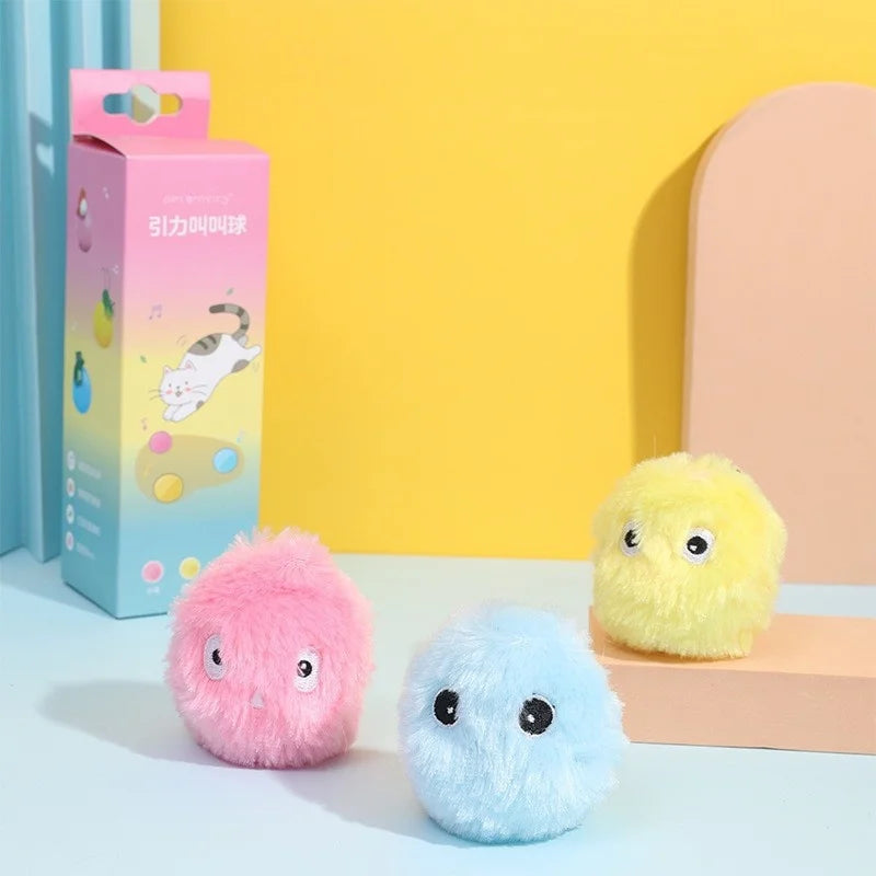 Ein rosa Plüschkatzenspielball und ein hellblauer Plüschball werden neben seiner Verpackung präsentiert.